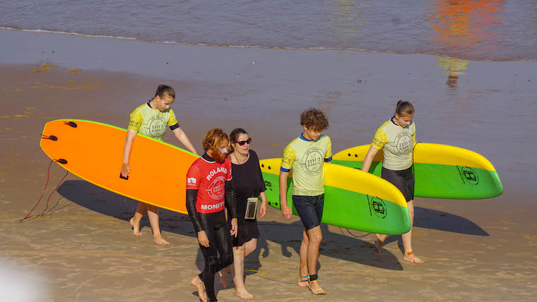 Moniteur et ses élèves allant marchant sur le sables avant leurs stages de surf à Biarritz